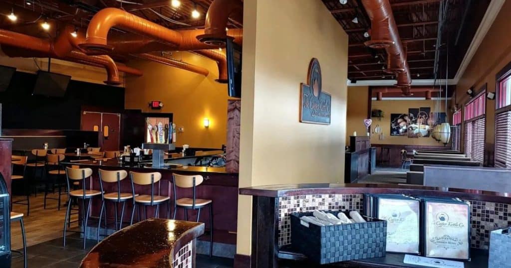 A welcoming entry way leading to an extensive wooden bar at The Copper Kettle.