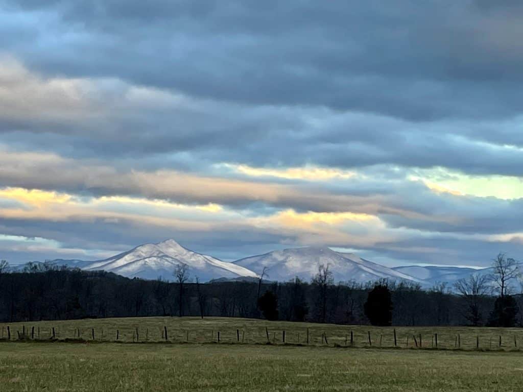 Snow-capped Peaks of Otter with sun peaking through clouds.